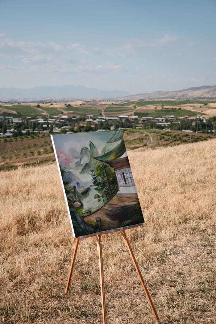 Outdoor scene with a painting easel showcasing landscape art in a vast field.